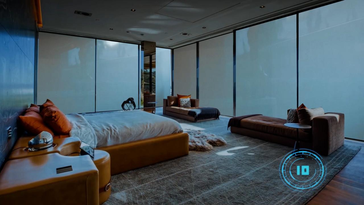 Mesmo quarto amplo com paredes de vidro no modo privativo, vidro leitoso e translúcido bloqueando a visão externa mas mantendo a luminosidade, cama com almofadas terracota, sofás de couro marrom, tapete cinza, ambiente aconchegante e privado, fotografia realista
